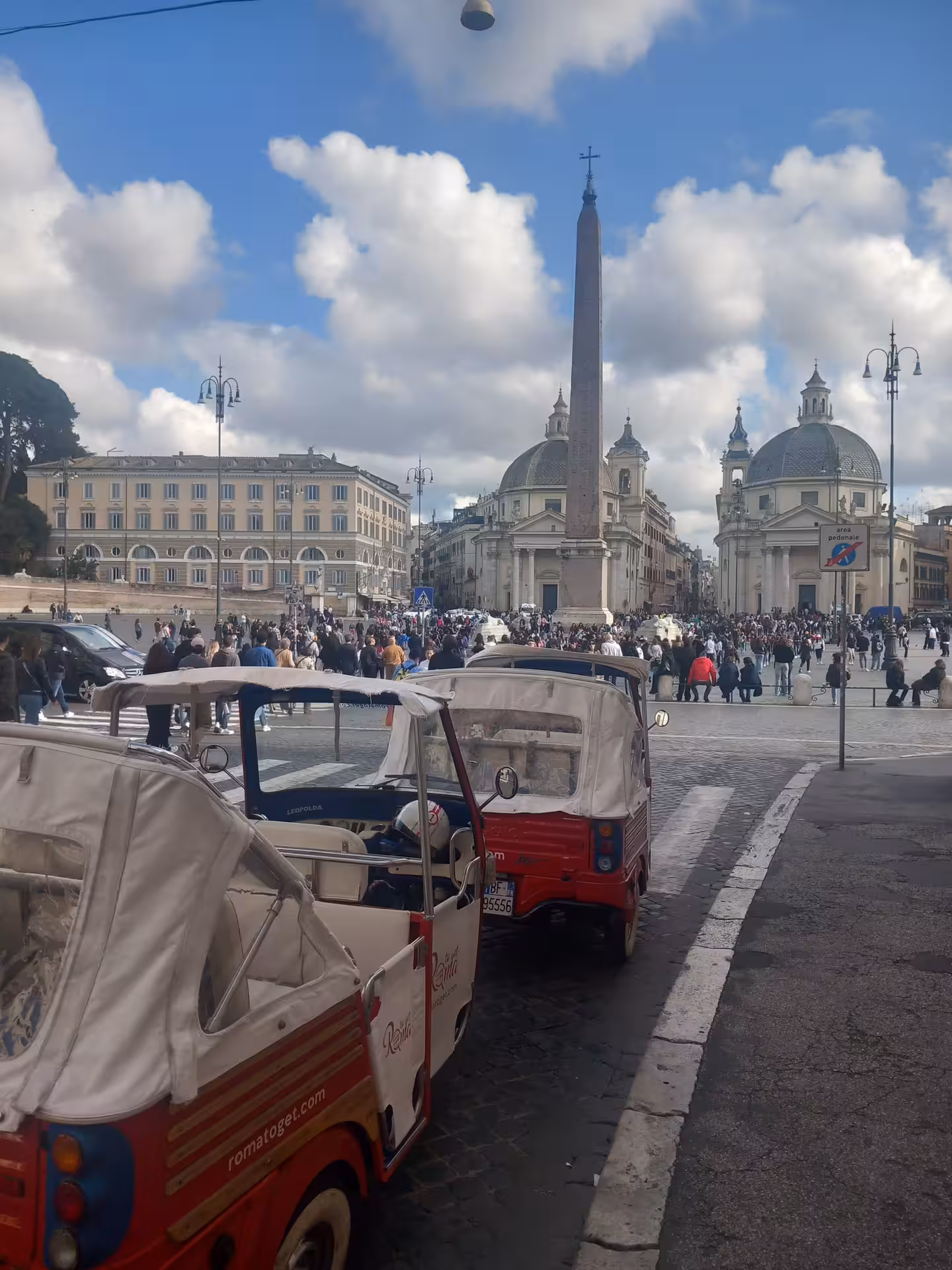 Red tuk-tuks parked at Piazza del Popolo, a popular stop on the Borghese Gallery Combo Tour in Rome.