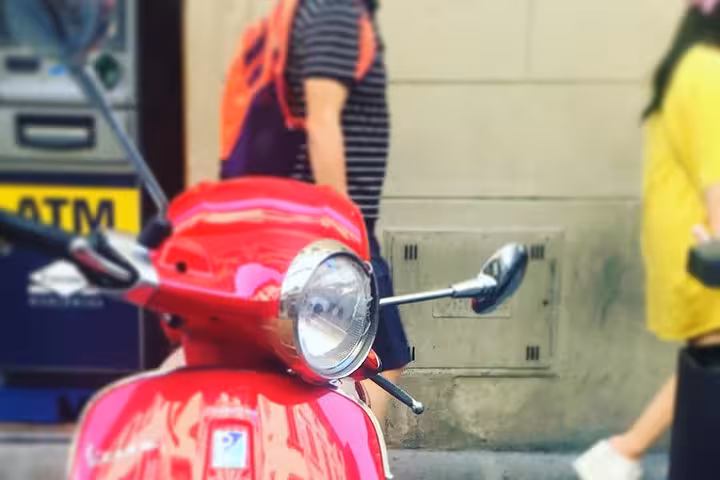 Red Vespa scooter parked on a busy Florence street, ideal for exploring the city's historic charm.