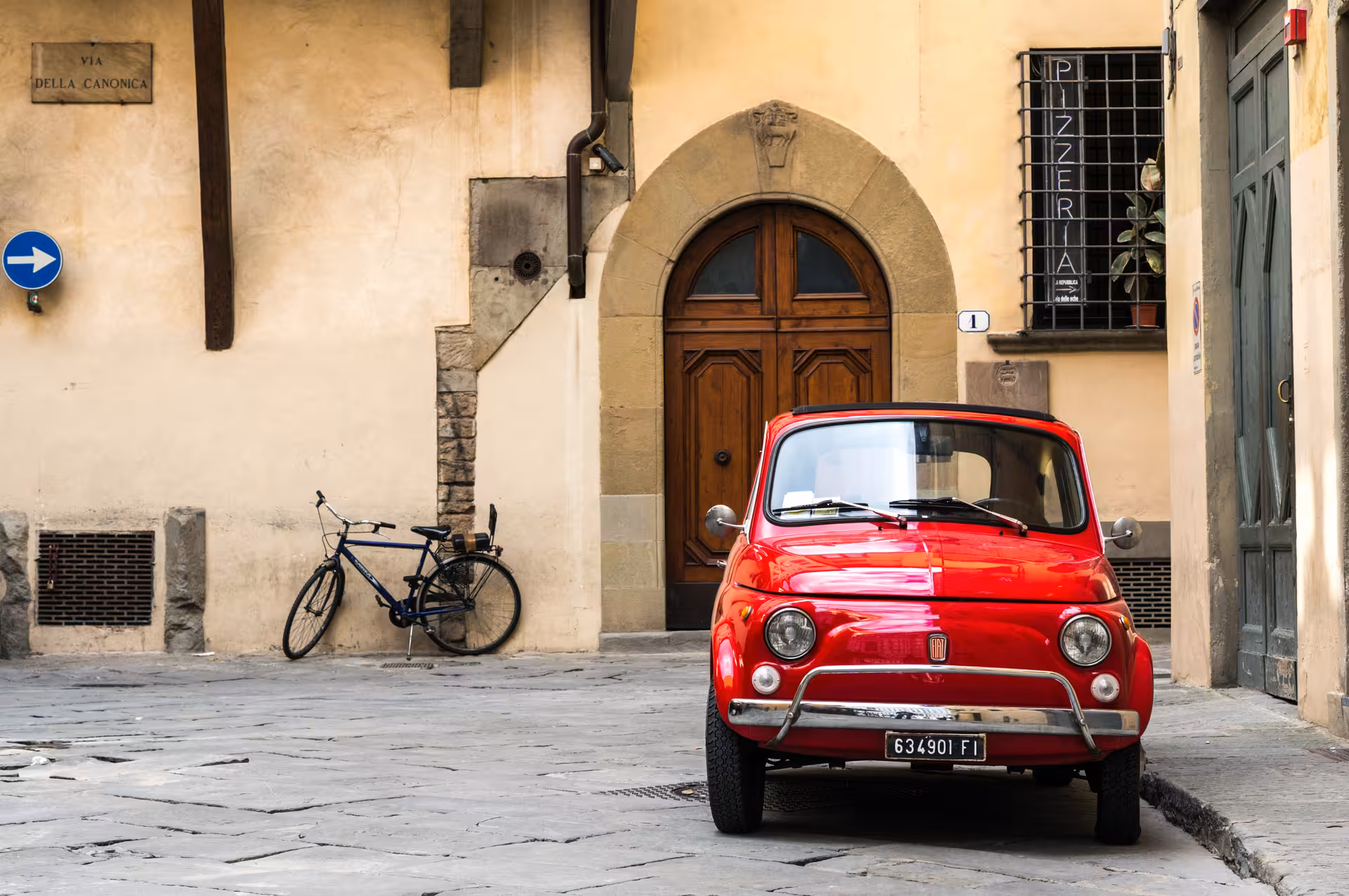 Red vintage Fiat 500 parked in a charming Italian street, ideal for a Chianti Classico wine tour.