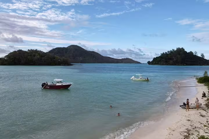 Scenic beach view with boats and swimmers, perfect for a snorkeling and fish feeding day trip in a tropical paradise.