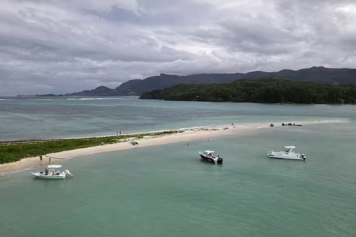 Idyllic island beach with anchored boats, offering a serene setting for a private snorkeling and lunch excursion.