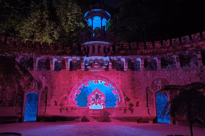 Illuminated Regaleira Palace at night, showcasing vibrant colors on historic architecture in Sintra tour.