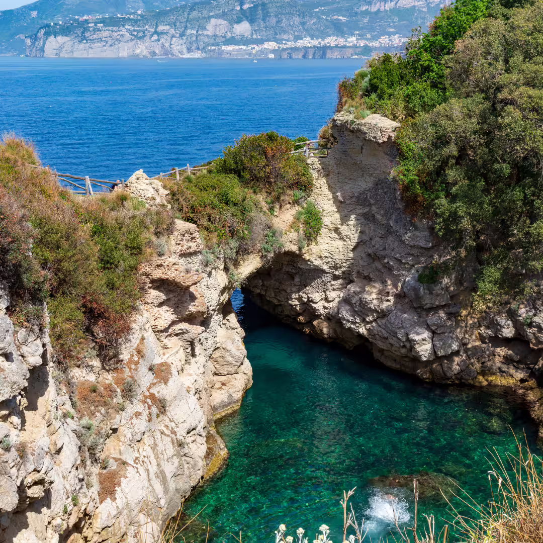 Scenic coastal path above Bagni della Regina Giovanna, overlooking emerald cove and Bay of Naples cliffs on trekking tour