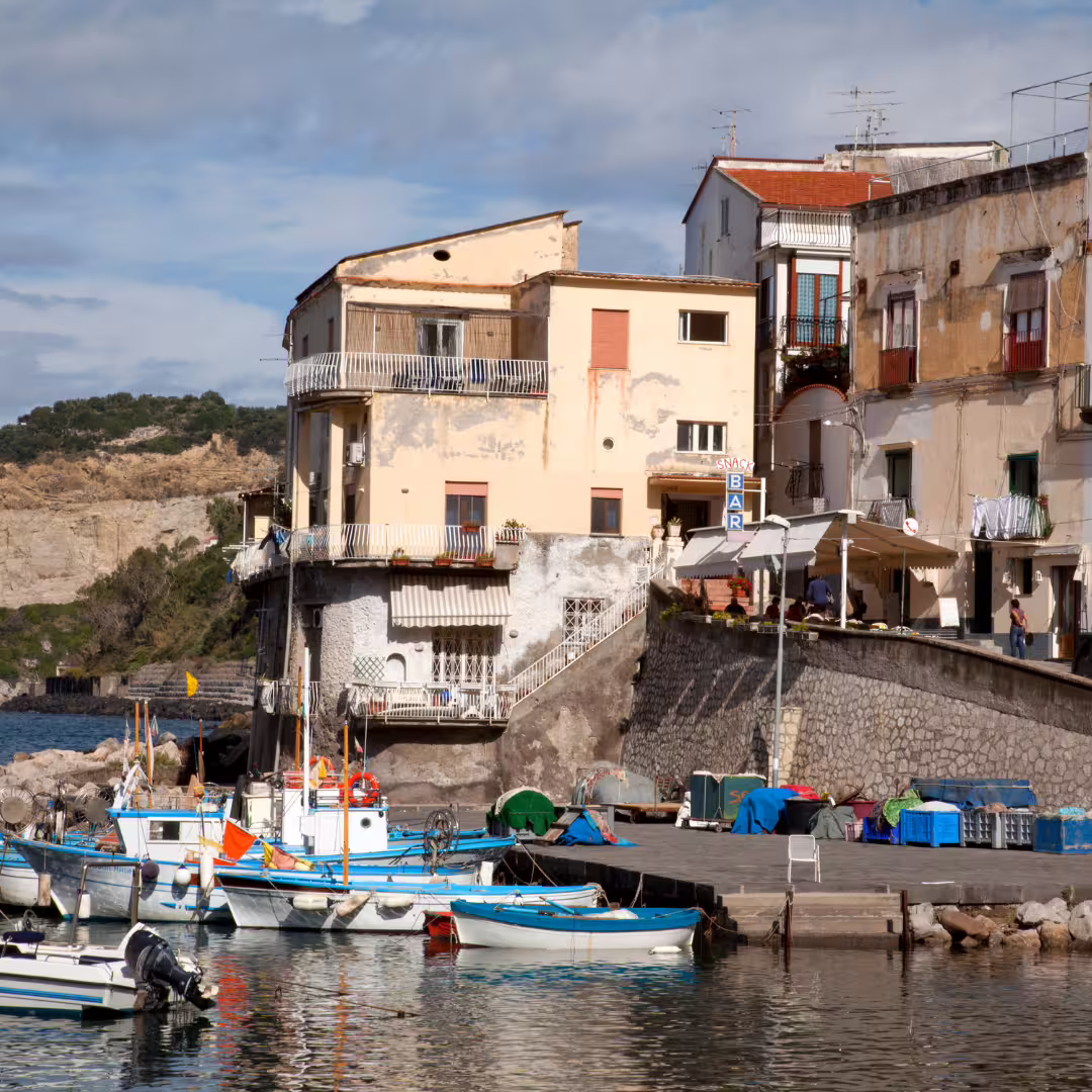 Colorful fishing boats moored below rustic seaside houses in Massa Lubrense, a charming stop on the Regina Giovanna trekking weekend