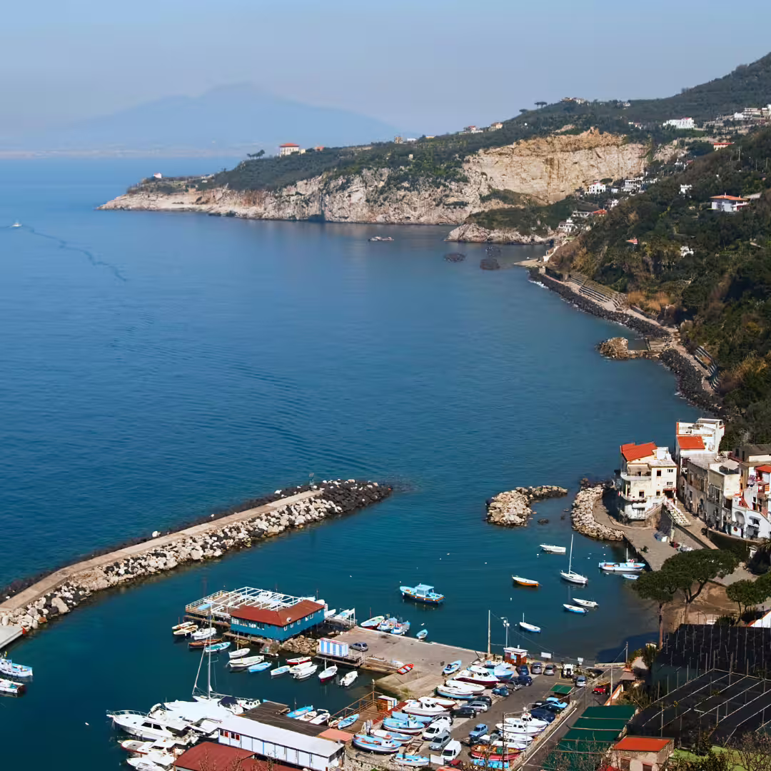 Panoramic view of Massa Lubrense marina and cliffs along the Sorrento Coast, a scenic highlight of the Regina Giovanna trekking tour