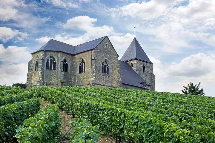 Ancient stone church nestled among lush vineyards under a blue sky in Reims, perfect for a private Champagne day trip from Paris.