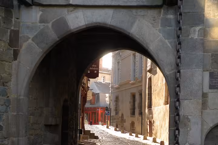 Discover the enchanting medieval stone archway leading to cobblestone streets in Rennes city center on a private tour.