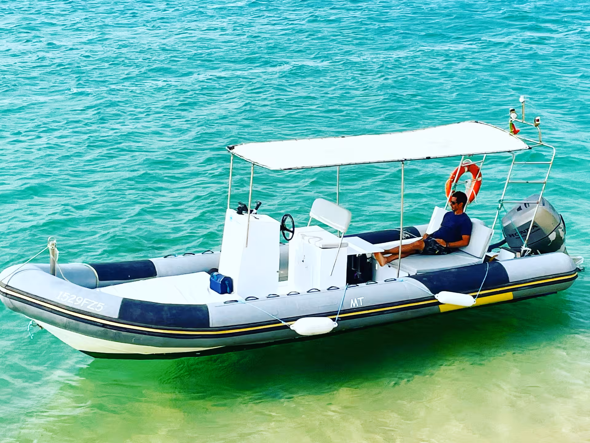 Rent-a-Boat Speed Boat Duarry speedboat anchored in shallow turquoise water with canopy, perfect lagoon cruise rental