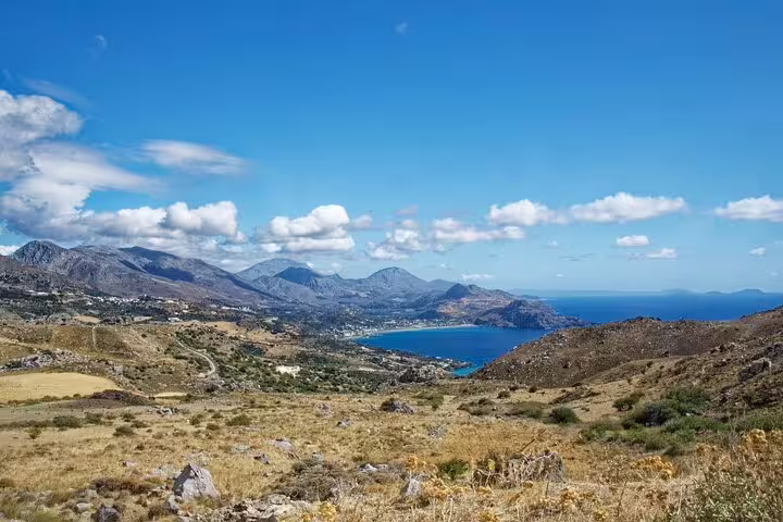 Scenic view of Rethymno Town's coastline with mountains and blue sea under a clear sky.