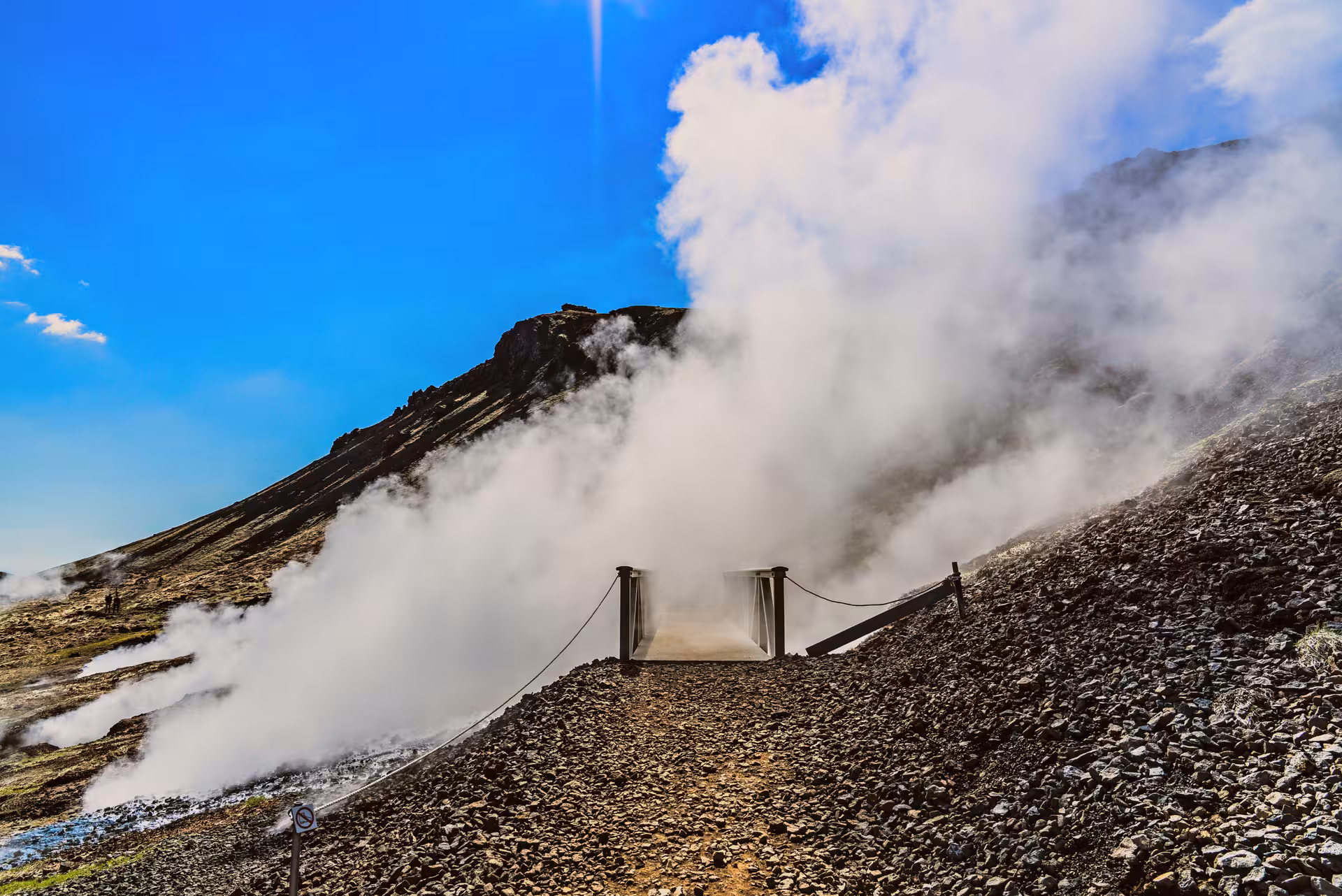 Footbridge through thick geothermal steam in Grændalur Valley on a private Reykjadalur circle hike in Iceland