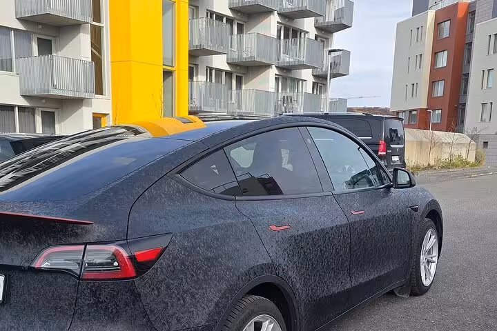 Sleek black car parked outside modern Reykjavik apartments, ready for Blue Lagoon private transfer.