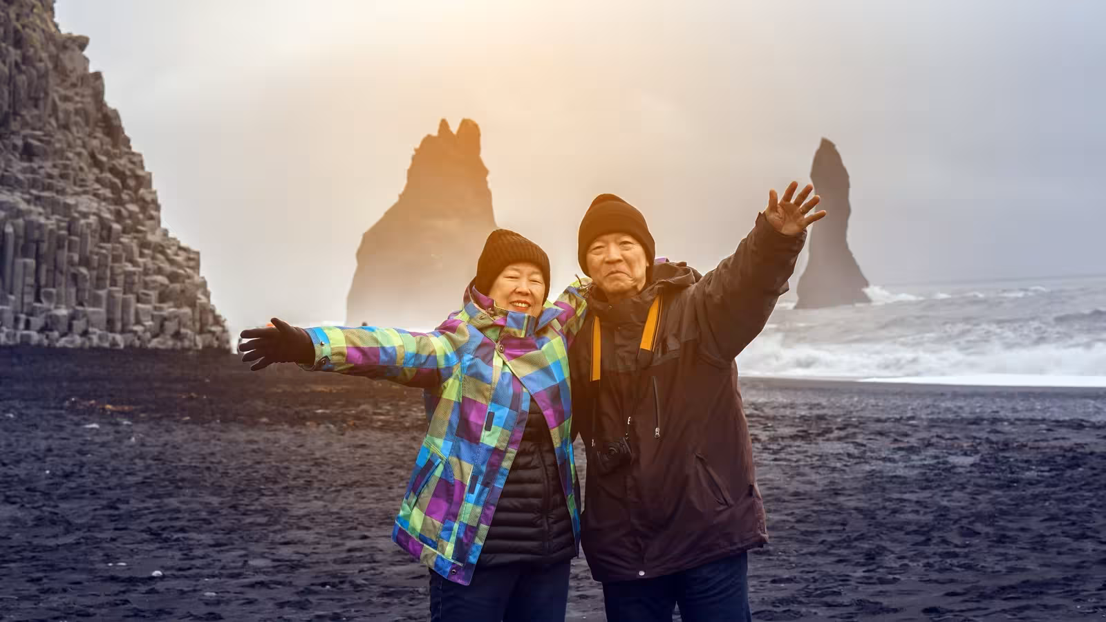 Tourists enjoying Reynisfjara Beach with iconic basalt columns and sea stacks, ideal for exploring Iceland's beauty.