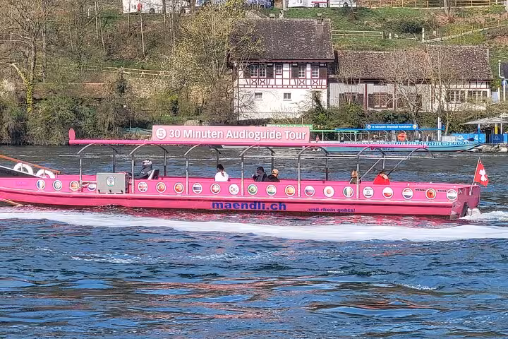 Pink tour boat cruising on the Rhine River near charming traditional houses in Stein am Rhein, Switzerland.