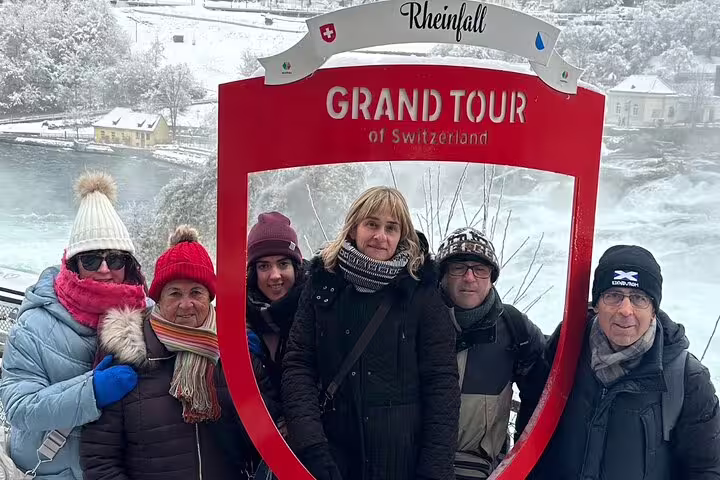 Visitors pose in Grand Tour of Switzerland frame with Rhine Falls backdrop on Zurich day trip.