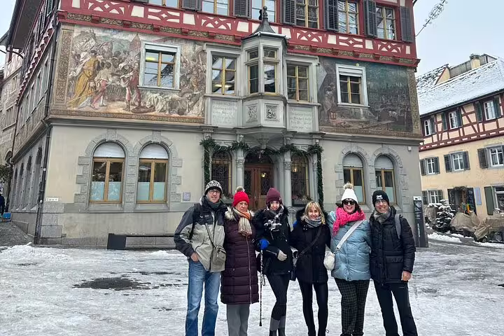 Tour group standing in front of historic mural-adorned building in Stein am Rhein on a Zurich Rhine Falls trip.