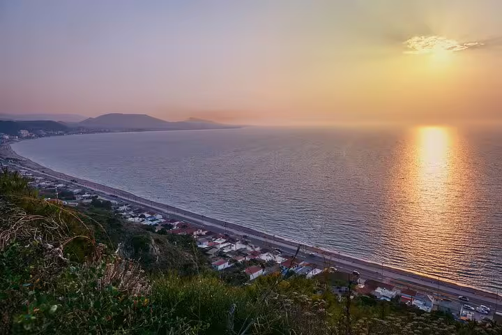 Scenic sunset view of Rhodes coastline from a hill, showcasing serene waters and vibrant horizon for night ride tour.