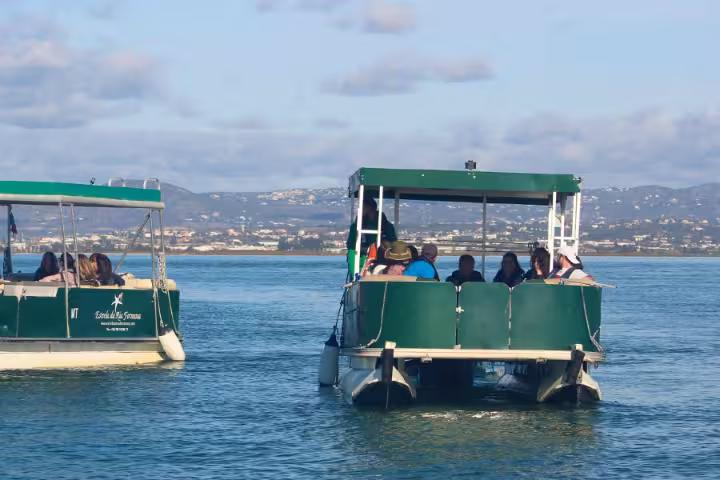Passengers on a Ria Formosa boat tour from Faro cruising the lagoon toward two island stops in Algarve, Portugal