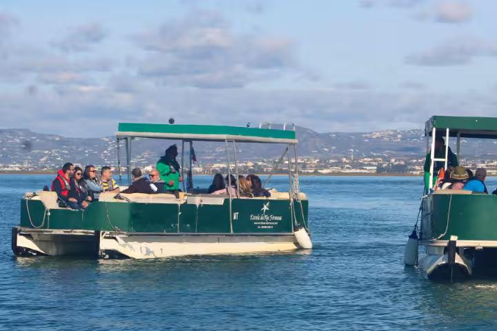 Passengers on a Ria Formosa boat tour cruising the lagoon near Faro, Algarve, with scenic coastline views