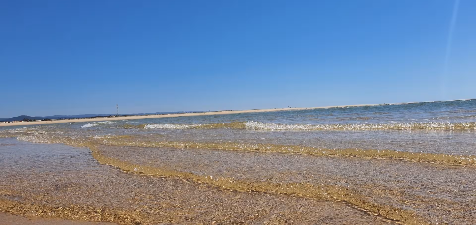 Gentle waves lapping on the sandy shores of Ria Formosa, offering serene views on a private Algarve tour.