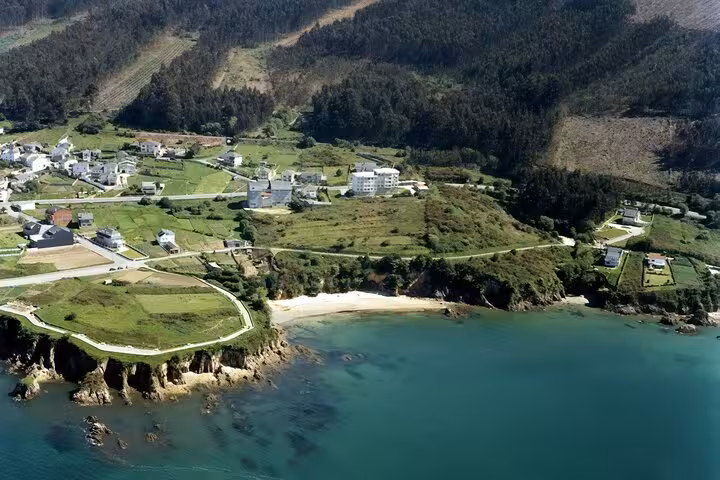 Aerial view of Rías Altas coastline with lush greenery and quaint village near Santiago, ideal for full-day tours.