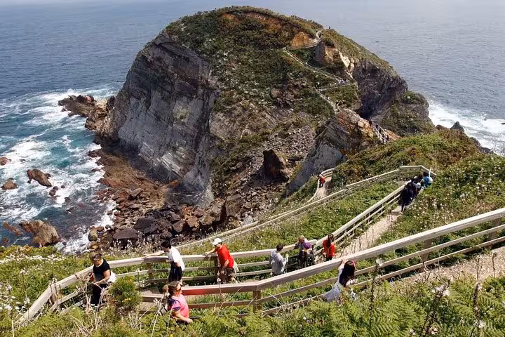 Tourists hiking the scenic trails of Fuciño do Porco with stunning coastal views and rugged cliffs.
