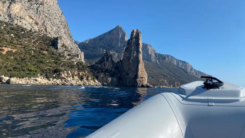 View from RIB boat heading towards Cala Goloritzé, highlighting stunning rocky cliffs and clear blue Mediterranean waters.