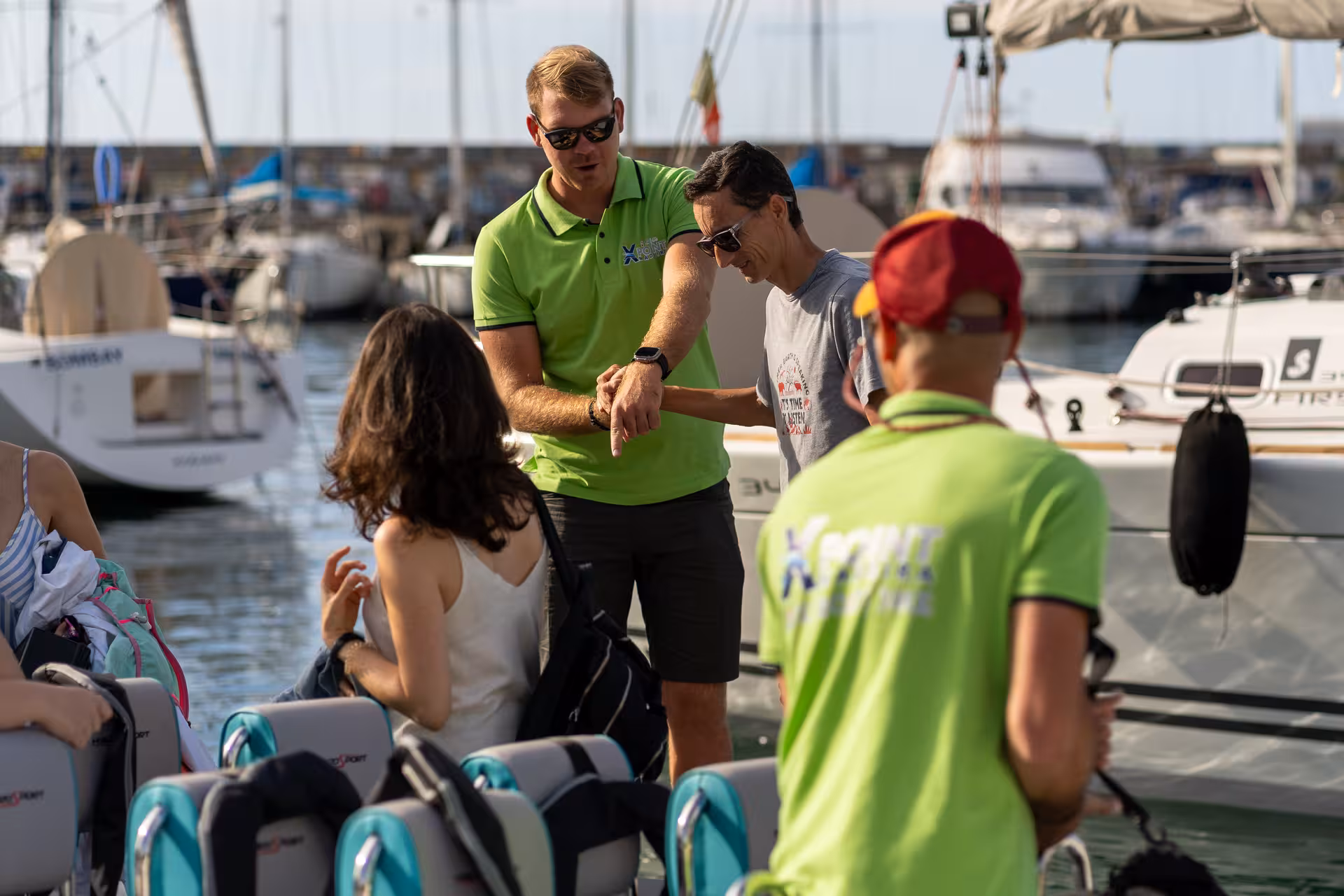 Guide explaining tour details to guests before RIB boat coastal sightseeing adventure at a vibrant marina.