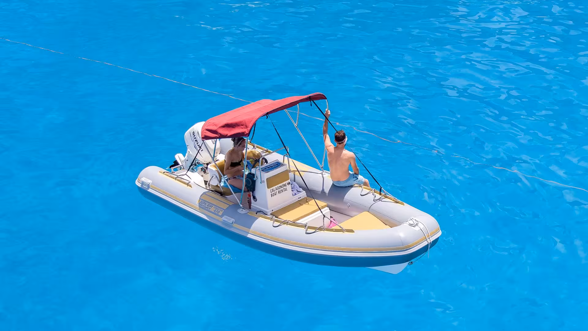 Aerial view of a RIB boat with two people enjoying the turquoise waters near Cala Gonone, ideal for up to 6 people.