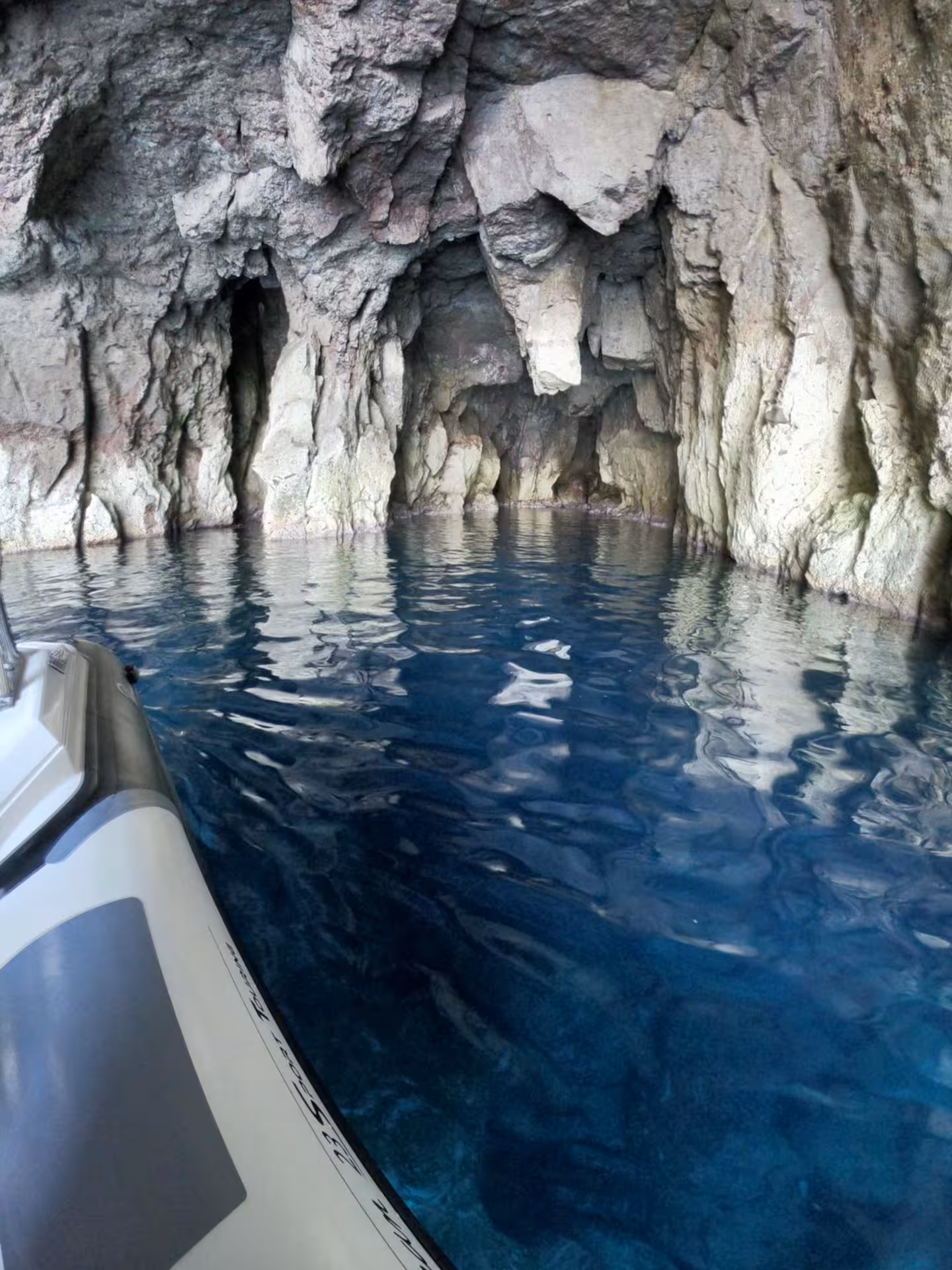 RIB boat navigating through serene blue waters in a rocky cavern on the Sant'Antioco to Carloforte tour.