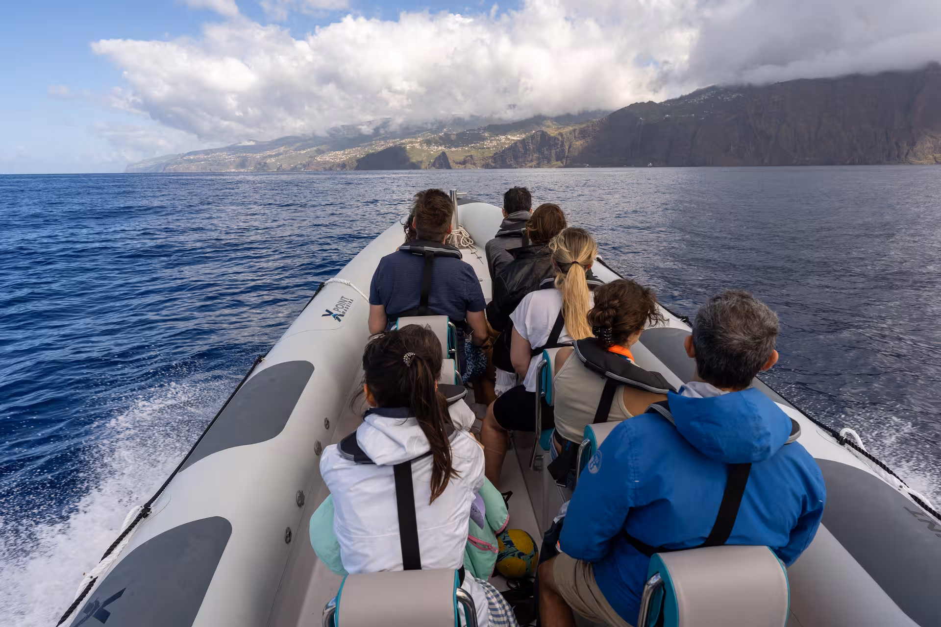 Group on RIB boat exploring vast ocean under cloudy sky, a top choice for dolphin and whale watching tours.