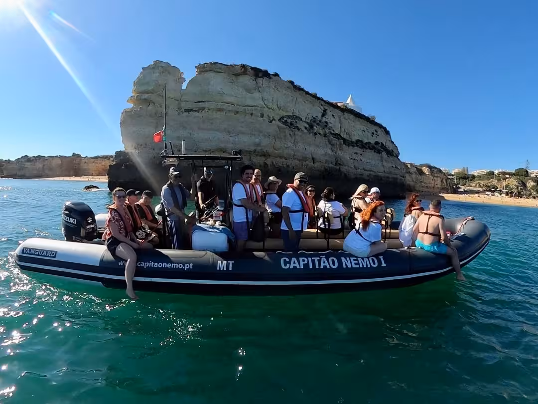 Small RIB boat tour exploring Algarve sea caves and marine wildlife, guests in life jackets cruising clear Atlantic waters