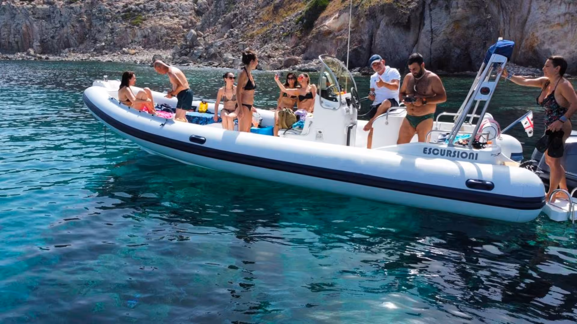 Tourists enjoy a scenic RIB boat tour on clear turquoise waters between Carloforte and Masua, Sardinia.