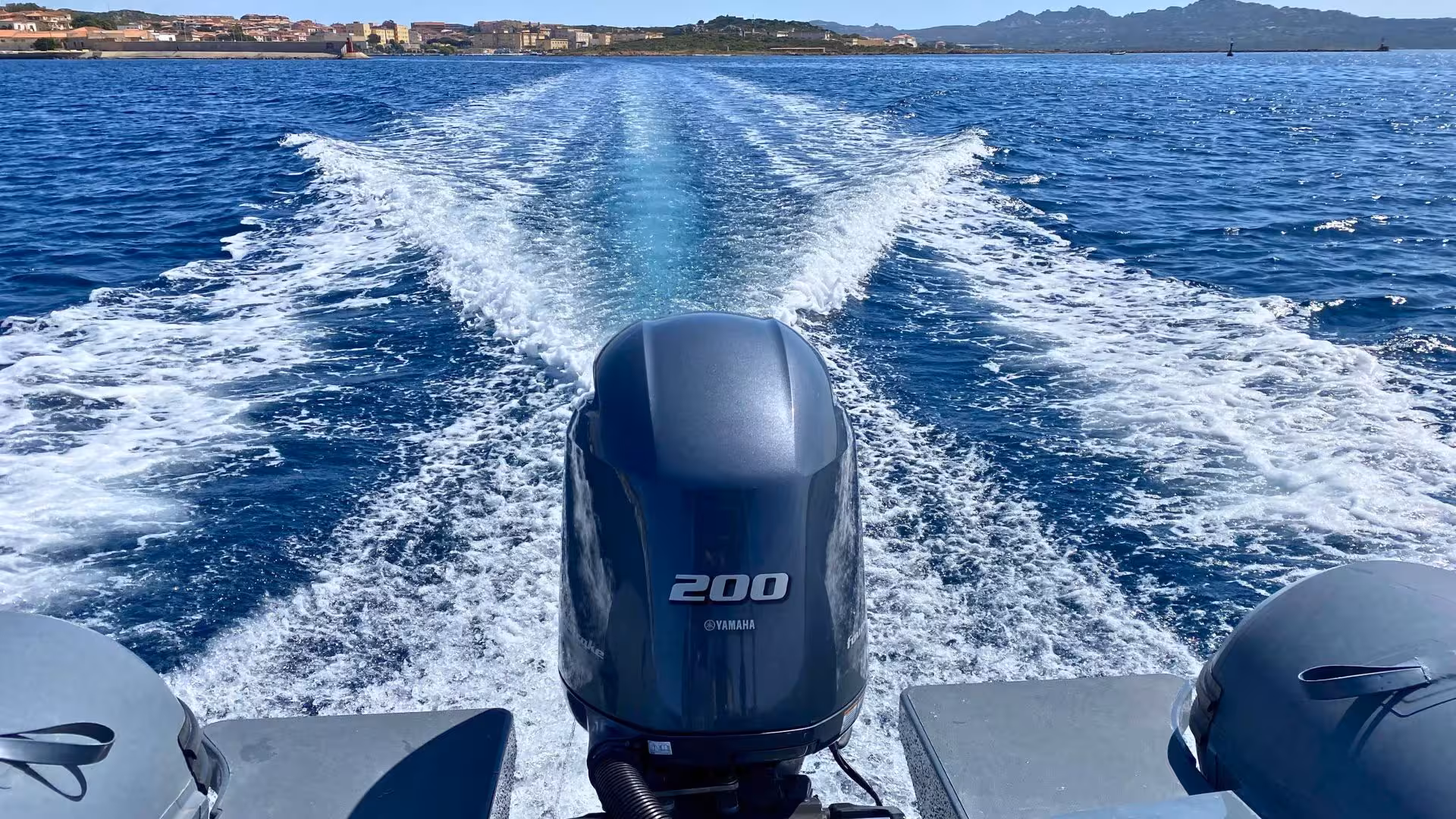 View from a RIB boat cruising through clear blue waters near the coast of Palau, showcasing stunning Corsican landscapes.