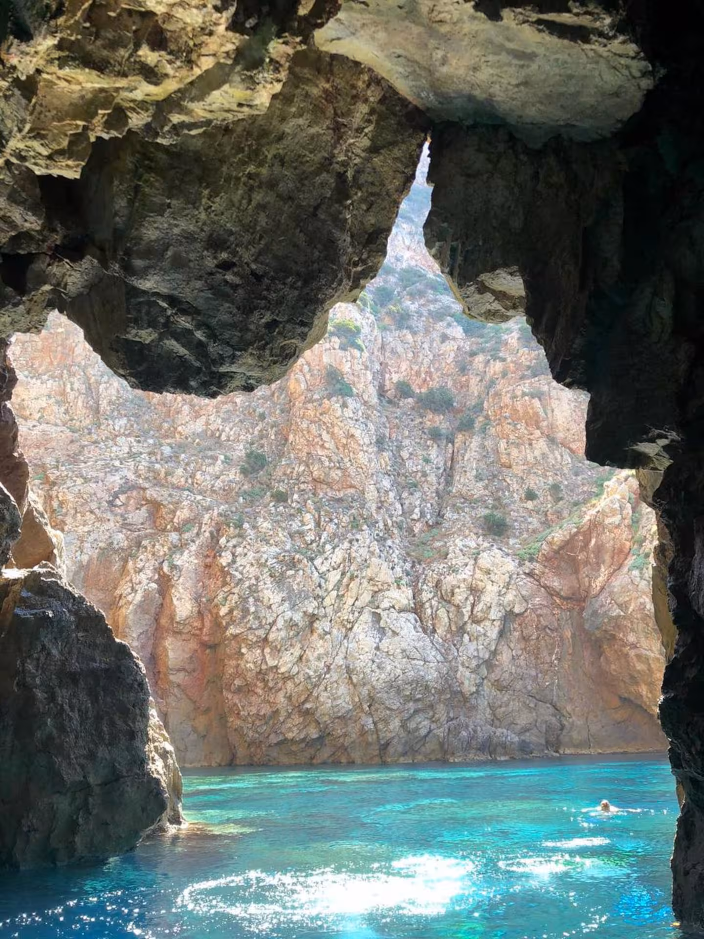 View from a cave opening to turquoise waters and rocky cliffs on a RIB tour between Carloforte and Masua.