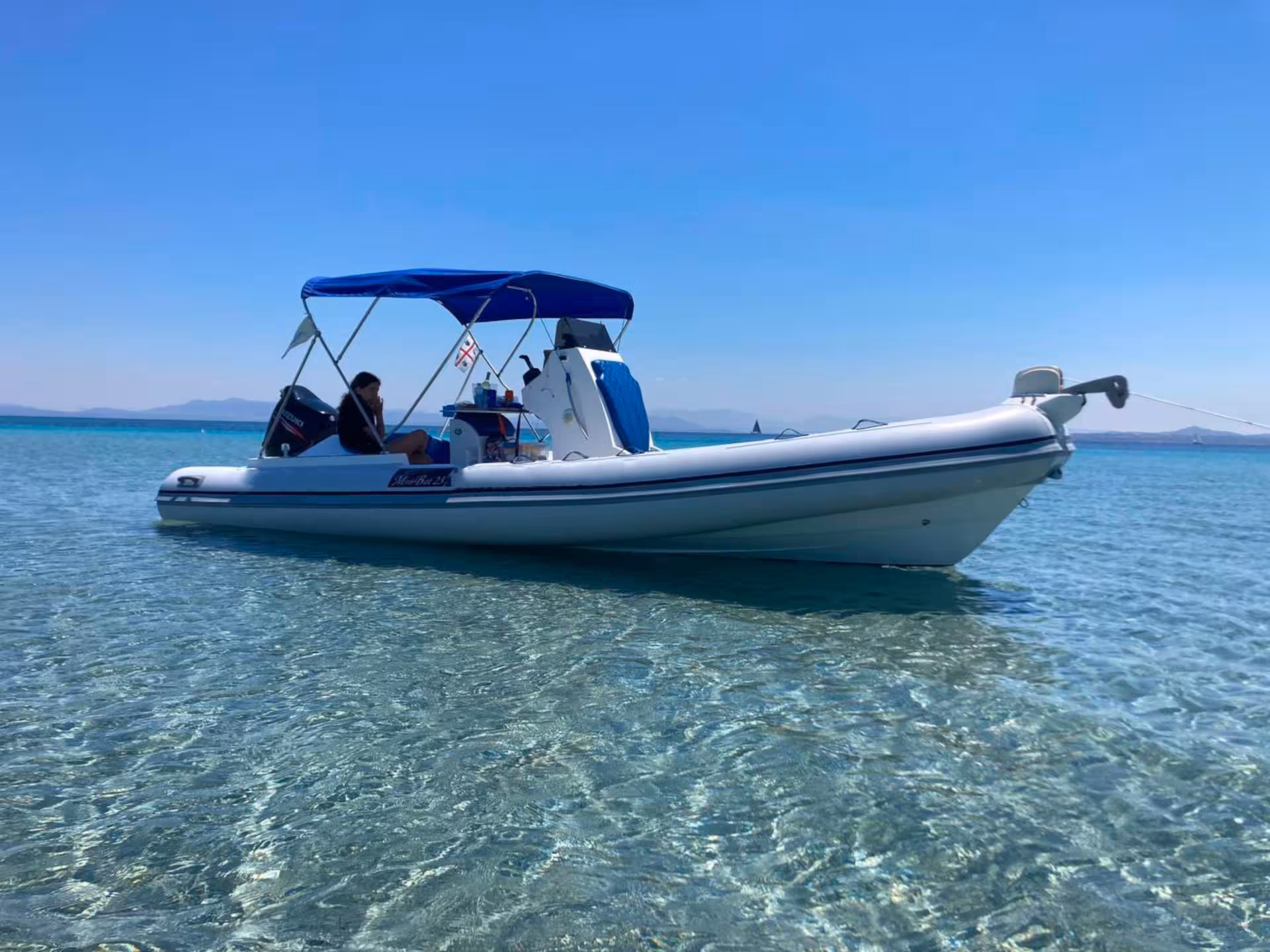 RIB with blue canopy gently floating on clear turquoise waters, ideal for exploring Carloforte and Masua from Sant'Antioco.