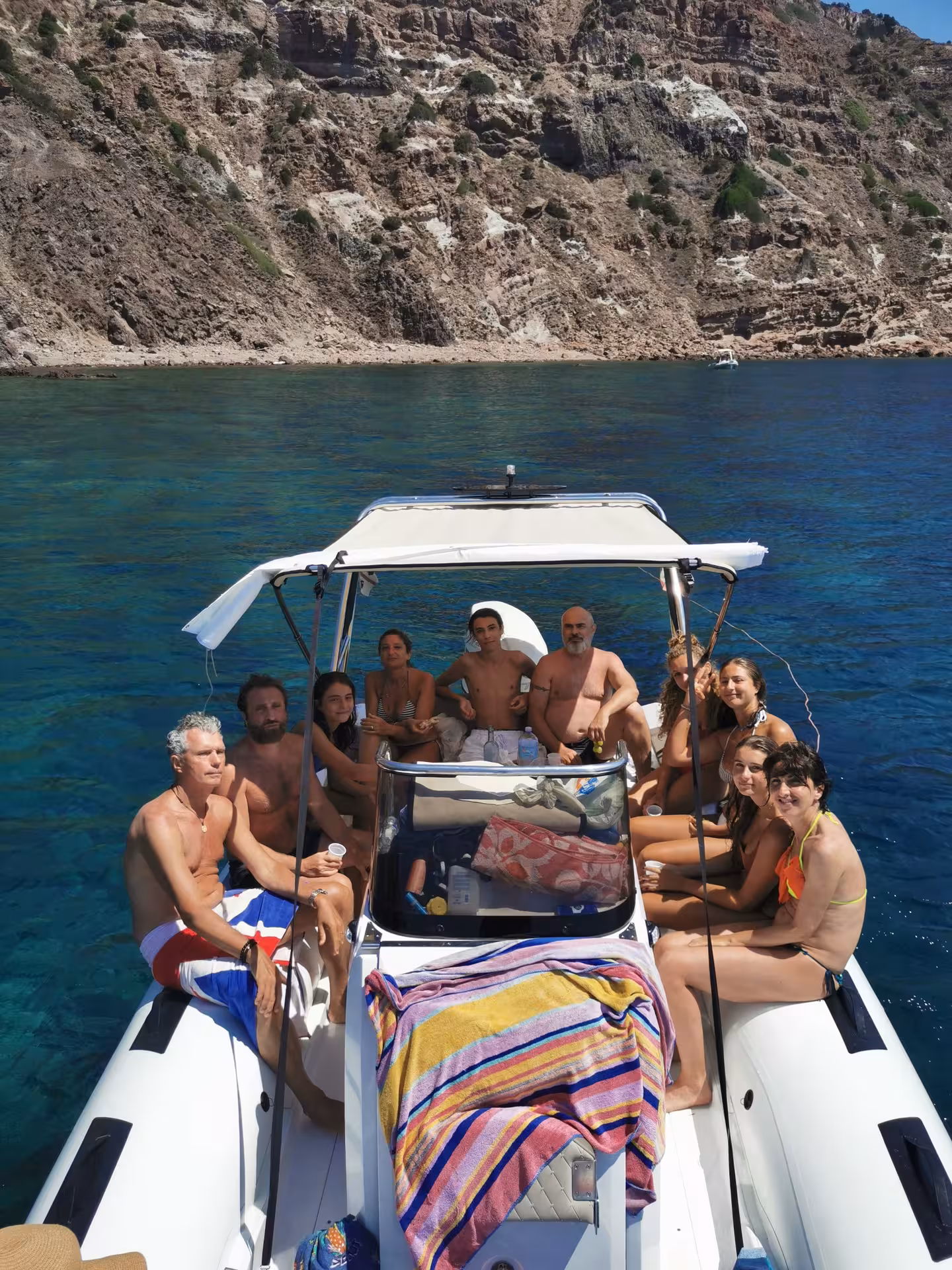 Group of tourists enjoying a RIB tour near rocky cliffs on the way to Carloforte.