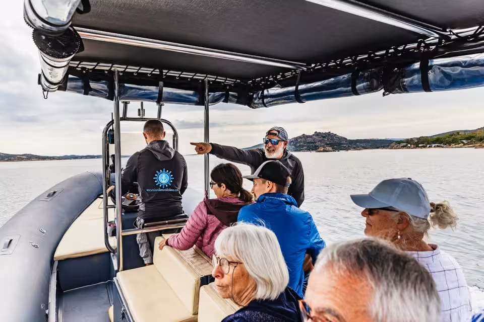 Tourists enjoying a guided RIB tour in La Maddalena Archipelago, with scenic views of the coastline and clear waters.