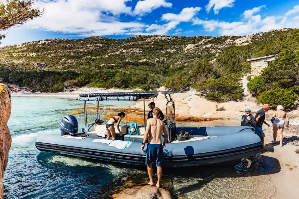 Tourists prepare for a RIB adventure on a secluded beach in the La Maddalena Archipelago, Sardinia.