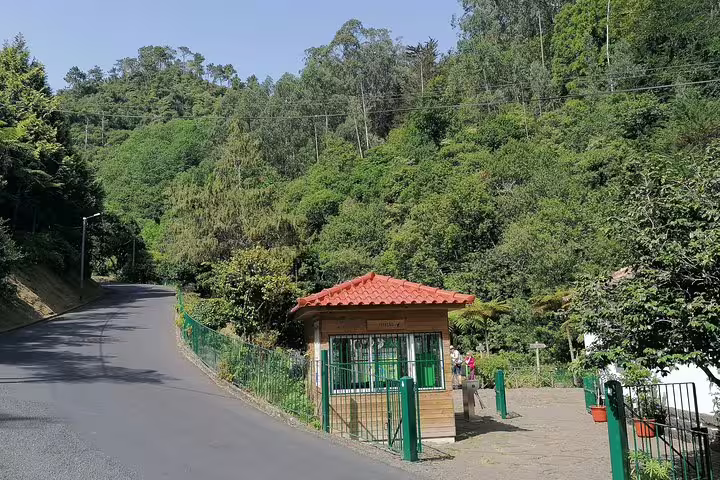 Charming red-roofed kiosk at the entrance of Ribeiro Frio, with a winding road and dense forest backdrop.