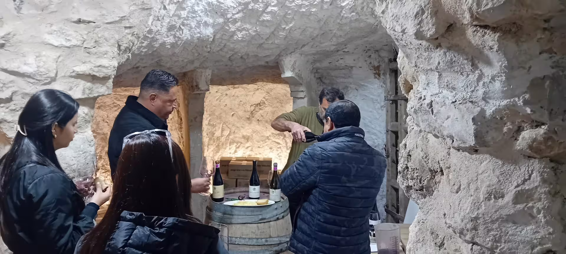 Wine enthusiasts enjoy a tasting session inside a rustic Ribera del Duero cellar with local selections.