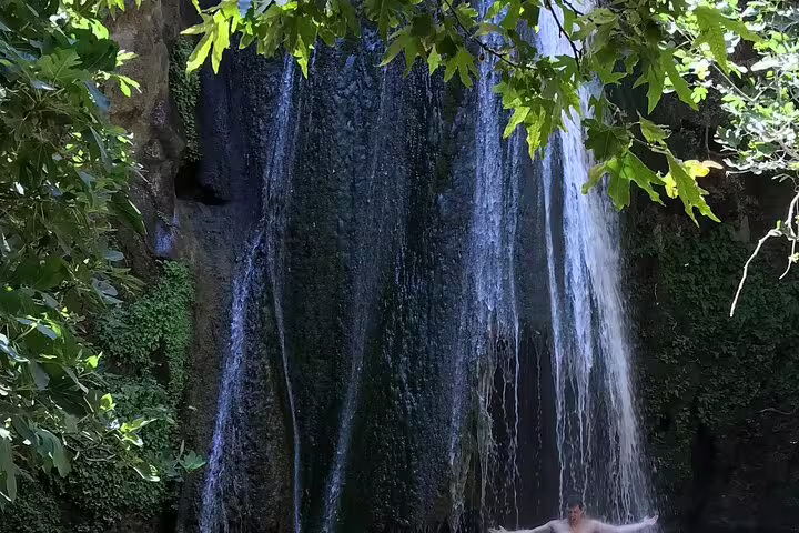 Tranquil scene of Richti Waterfall cascading down lush greenery, perfect for a refreshing escape in nature.