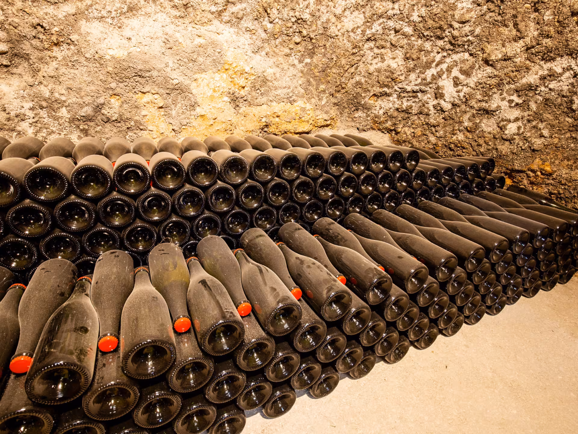Rows of dusty wine bottles aging in a rustic Rieti countryside cellar, ideal for wine enthusiasts.