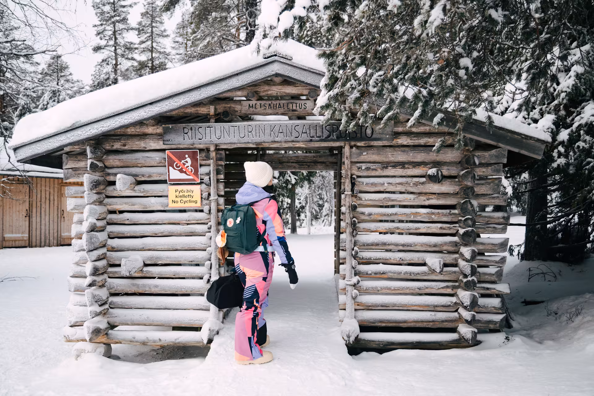 Hiker entering Riisitunturi National Park for a winter photography adventure, surrounded by snow-covered trees.