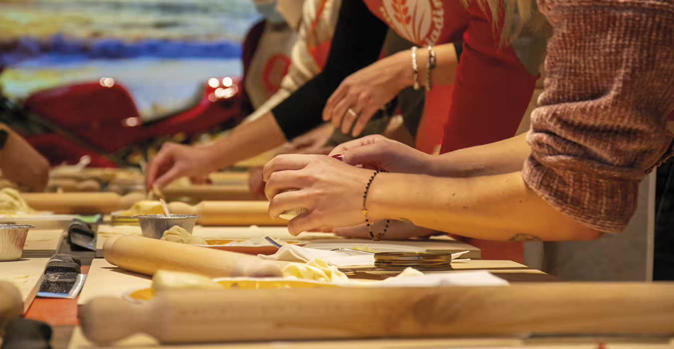 Hands shaping dough with rolling pins during a piadina-making workshop at Rimini’s first Piadina Museum