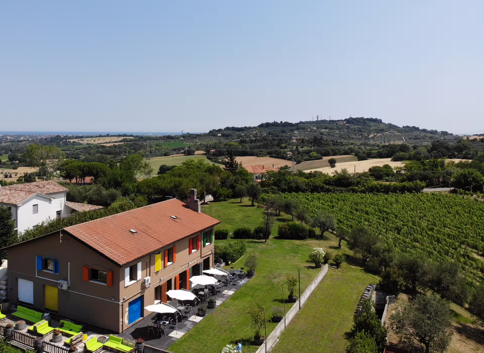 Aerial view of Rimini vineyard landscape with rustic farmhouse, ideal for San Valentino DOC wine tastings.