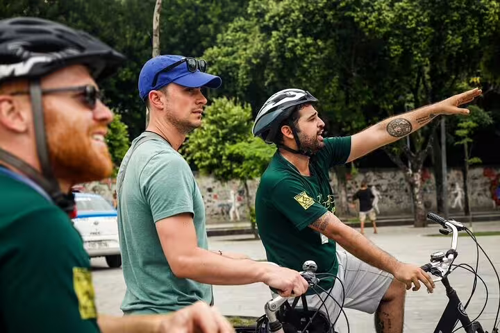 Tour guide points out landmarks to cyclists during an engaging Rio bike tour through lush city streets.