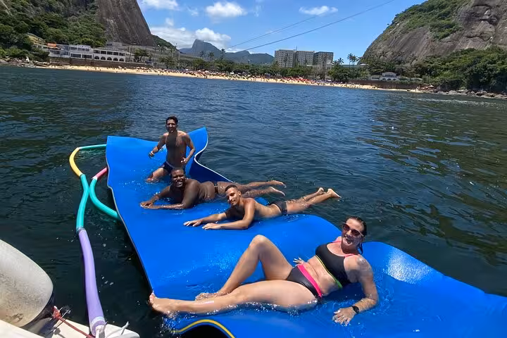 Guests relaxing on floating mat at Rio de Janeiro catamaran cruise, 5-hour private tour with BBQ and open bar