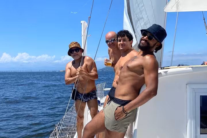 Group sunbathing on Rio de Janeiro catamaran deck with open bar, private 5-hour sail and BBQ vibe