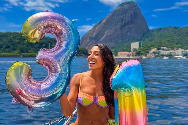 Guest celebrating on Rio catamaran sailboat with open bar, colorful balloons and Sugarloaf Mountain backdrop
