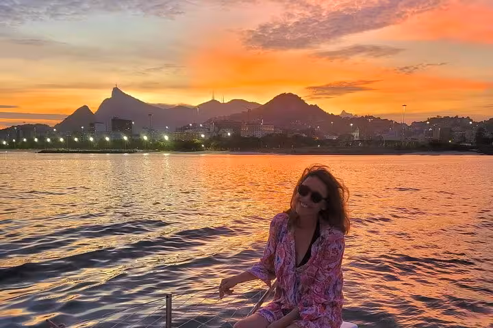 Smiling guest on Rio catamaran at golden sunset, 5-hour sailboat cruise with BBQ and open bar